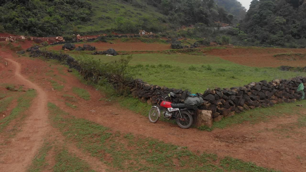 Moto Honda Win con grande zaino parcheggiata in un prato verde in Vietnam, vista aerea
