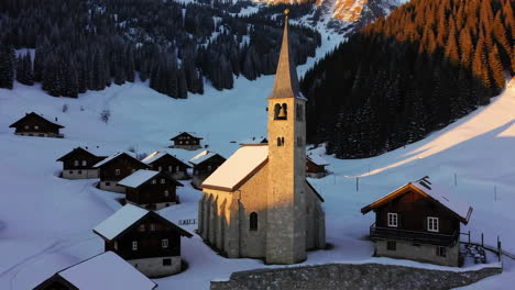 Snowy Alpine Village with Church at Sunrise