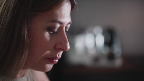 close up side view of young lady eating with serious expression, featuring soft bokeh lights in blurred background, wearing sleeveless top indoors, showing focus on food