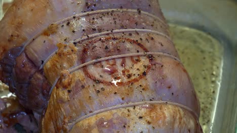 apuñalar un asado de cerdo a medio cocer en una bandeja para asar de vidrio con un cuchillo para carne
