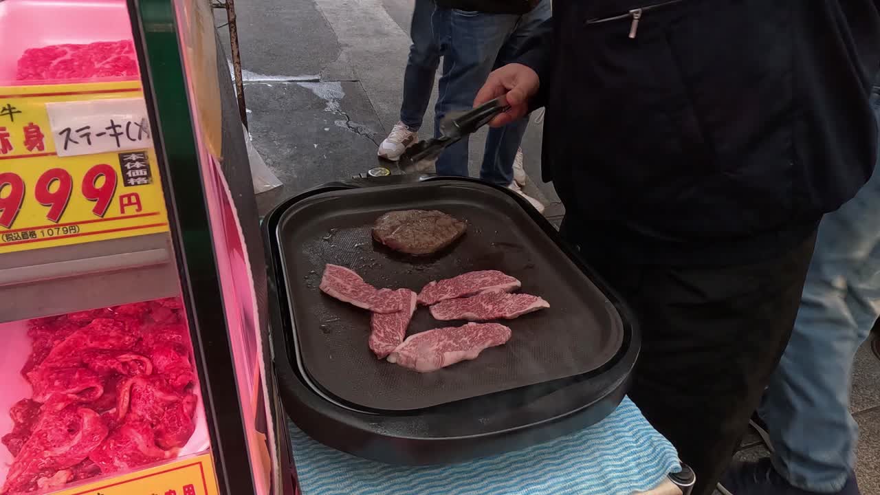 야외에서 핫플레이트에 고기를 요리하는 사람.