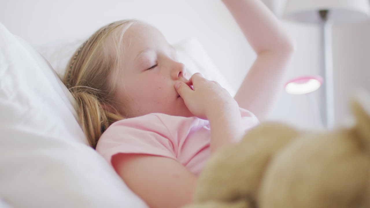 침대에서 깨어나는 백인 소녀의 측면 시각