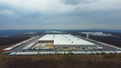 a drone pan moves toward a shipping center in schuylkill county, revealing hundreds of containers neatly arranged with the soft blue mountains rising in the distance industry meets natural beauty.