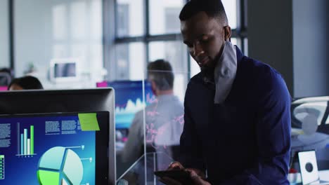 Portrait-of-african-american-with-man-lowered-face-mask-using-digital-tablet-at-modern-office