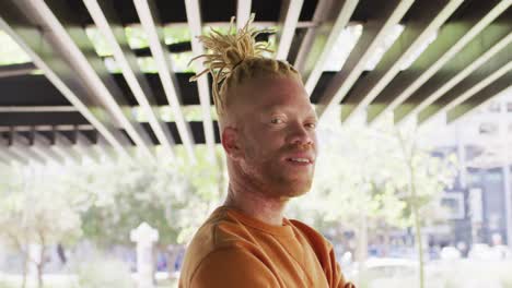 portrait of smiling albino african american man with dreadlocks in park looking at camera