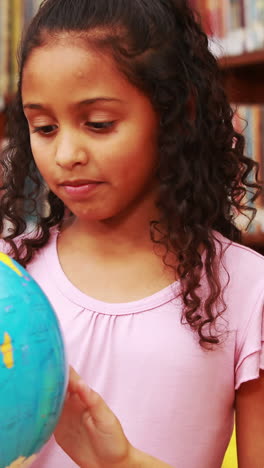 niñas mirando el globo en la biblioteca