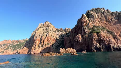 Reddish-orange-rocks-of-Calanques-de-Piana-seen-from-tour-boat-on-Mediterranean-Sea-in-Corsica-in-summer-season,-France