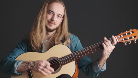 Caucasian-young-man-playing-guitar-and-singing-on-camera.