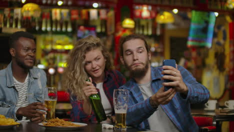 happy male friends taking selfie and drinking beer at bar or pub. people leisure friendship technology and party concept - happy male friends taking selfie