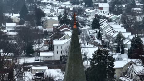 church steeple in front of snow covered houses in american town