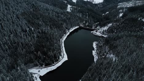 aerial shot over a water reserve and a dam during winter over a snowy landscape, auvergne rhone alpes region, france