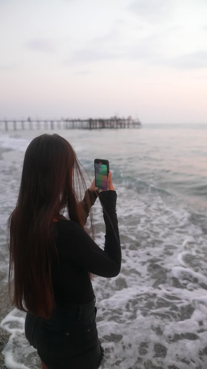 mujer tomando una foto en la playa al atardecer
