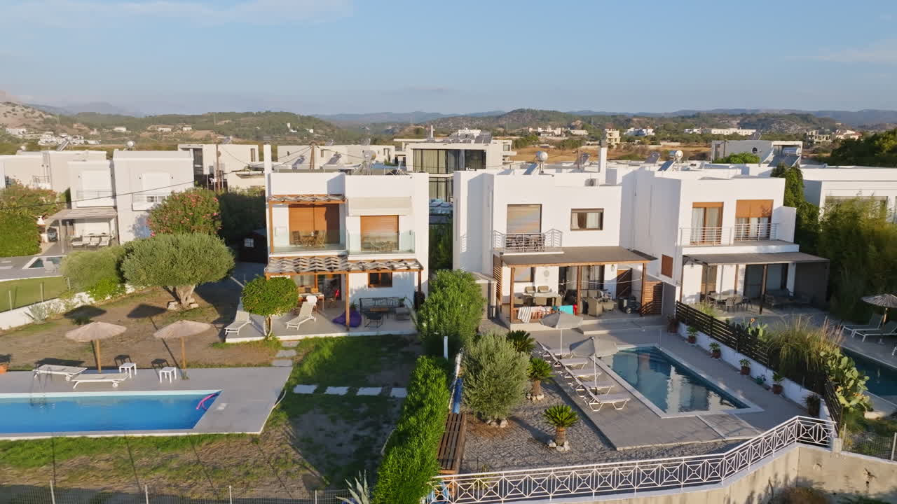 Aerial tracking shot in front of a deluxe holiday villas, golden hour in Greece
