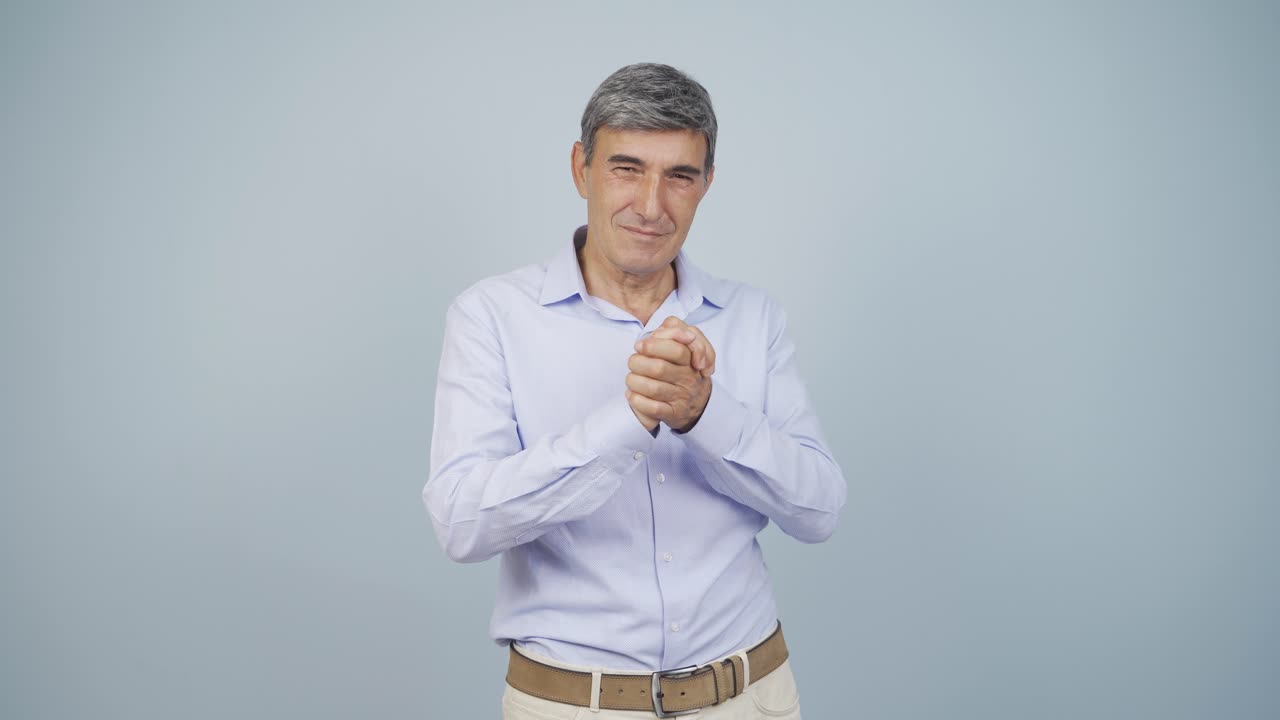 un anciano mirando a la cámara haciendo una señal de confianza.