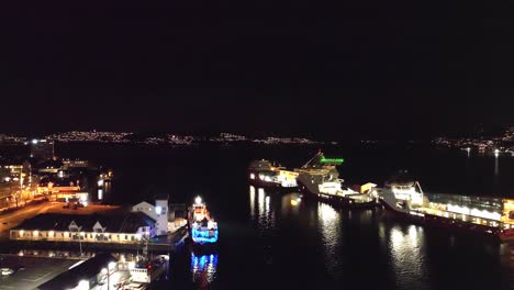 Vagen-Y-Byfjorden-En-Bergen-Durante-La-Medianoche-Del-Año-Nuevo---Barcos-Amarrados-Al-Costado-Y-Fuegos-Artificiales-Aleatorios-Vistos-En-El-Fondo-De-La-Isla-Askoy---Antena-Nocturna-Noruega