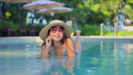 A-happy-young-Asian-woman-relaxing-in-a-swimming-pool-at-a-hotel-resort