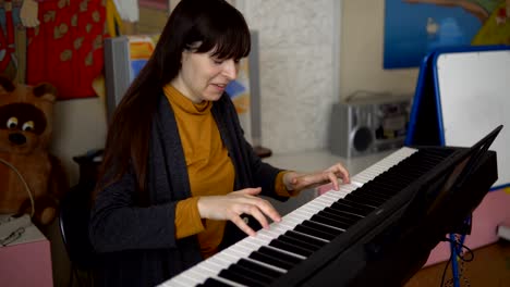 a young woman plays an electronic synthesizer, her hands touch the keys.