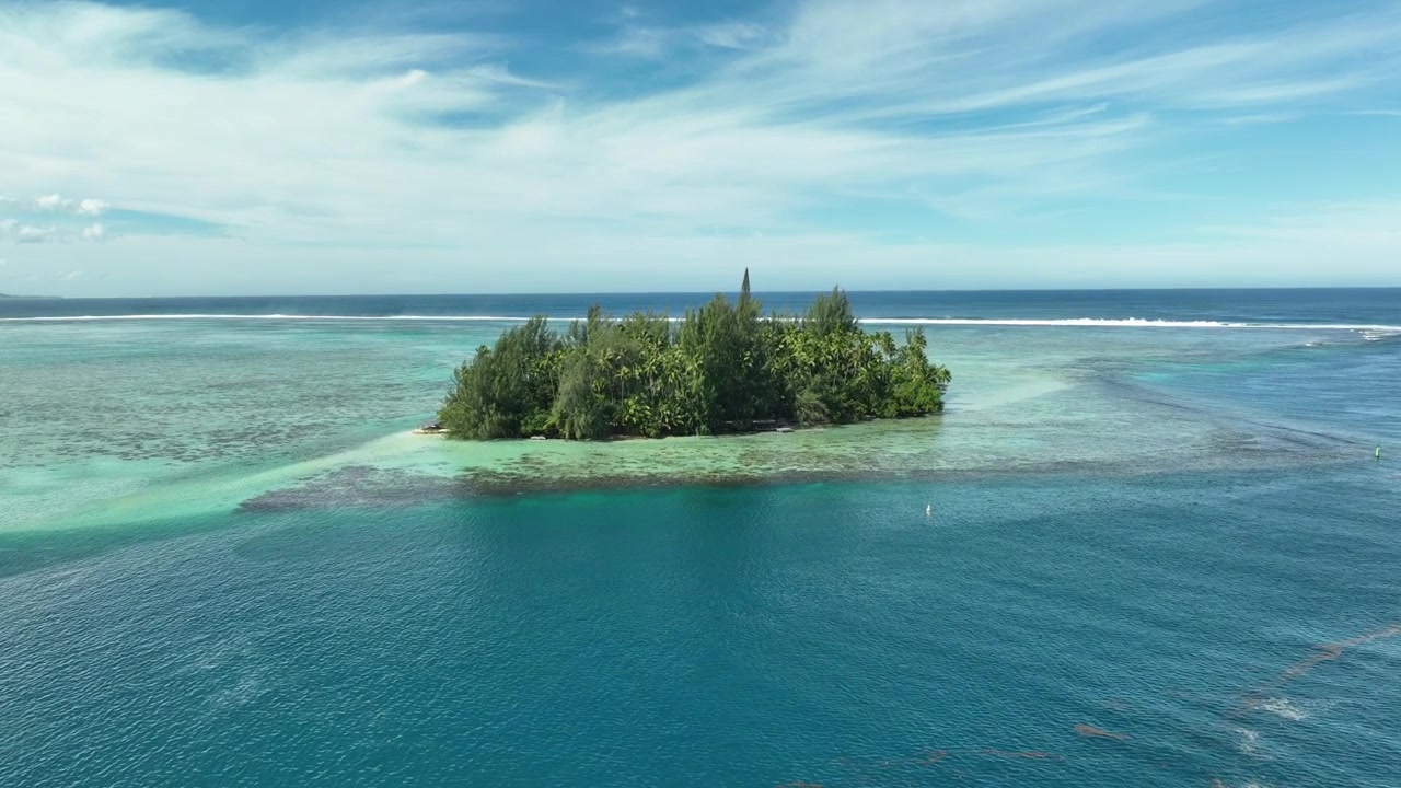 Una piccola isola remota circondata dalla barriera corallina e da acque oceaniche blu a Tahiti