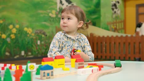 2-year-old toddler girl playing with toy cars in a tiny town set and suddenly sneese - slow-motion