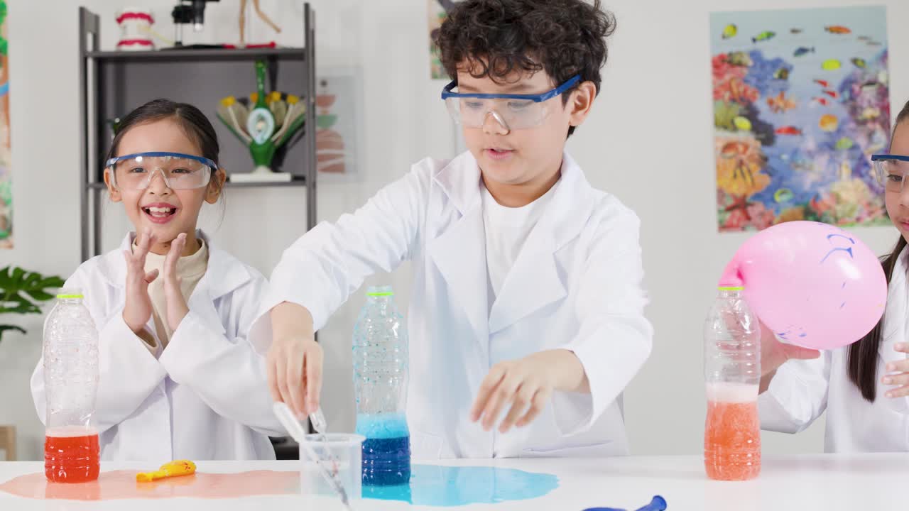 Anak-anak Asia mengenakan jas lab melakukan eksperimen sains menggembungkan balon menggunakan reaksi kimia.