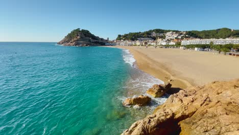 Bahía-De-Tossa-De-Mar-Vista-Desde-El-Castillo-Hasta-La-Playa-Con-Arena-Gruesa-Y-Agua-De-Mar-Azul-Turquesa-Antiguo-Pueblo-Pesquero-Medieval-Amurallado-Mar-Mediterráneo