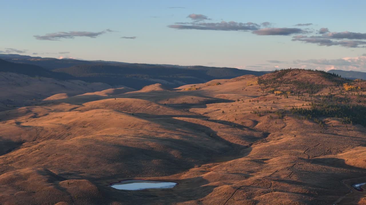 paleta crepuscular: vista aérea de la puesta de sol sobre el desierto cubierto de hierba, el lago central y las colinas boscosas