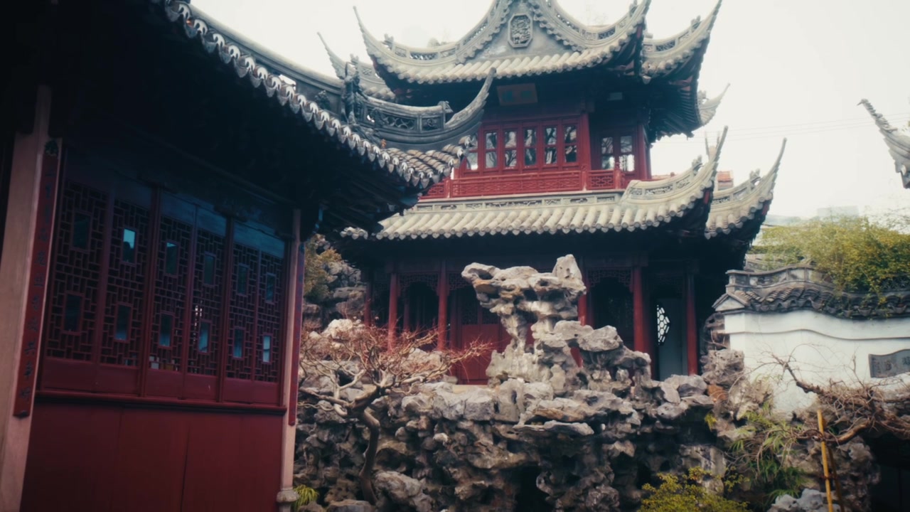 Sisäpihanäkymä Yu-puutarhasta, Shanghaista, esittäen useita Ming-dynastian paviljonkirakennuksia. Keskellä kaksikerroksinen punainen lakkahalli, jossa on kaksinkertainen koristeellinen katto ja ylöspäin kaartuvat räystäskulmat.