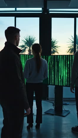team of programmers analyzing green matrix code on large screens