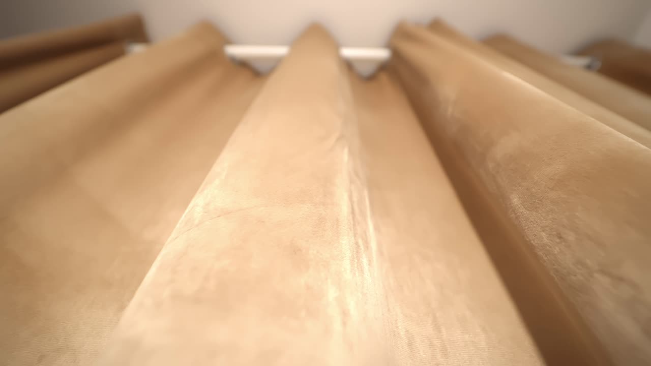 Morbide pieghe di tendaggi beige in luce calda, creando un elegante sfondo tessile per l'interior design, l'arredamento di hotel e l'arredamento di case di lusso