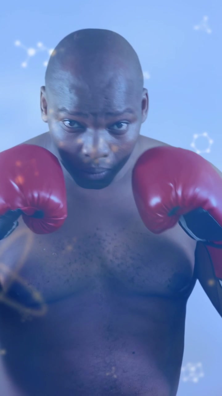 Vertical video: Camera cue male boxer guard up jabbing for sport with red gloves particle overlay