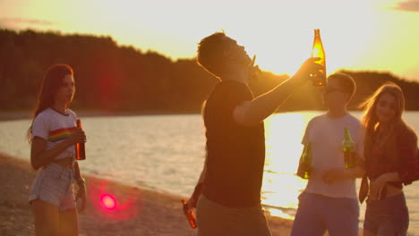 the brutal man in black t-shirt is dancing on the open air party with beer. it is crazy and hot beach party with the best friends in the perfect mood.