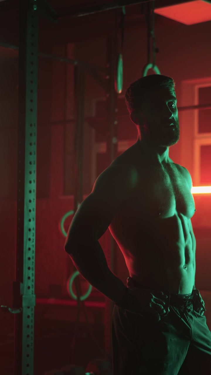 Uomo muscoloso in posa in una palestra buia con luci al neon