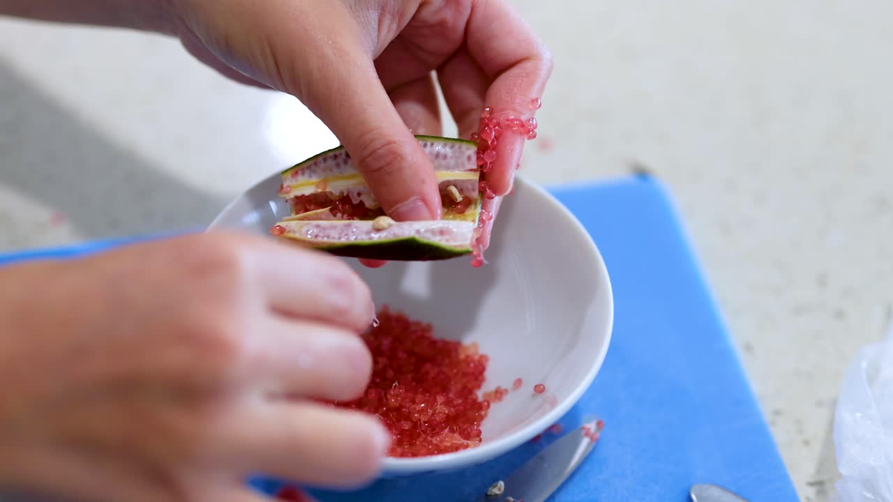 Hands extracting finger lime pulp into a bowl on a kitchen counter with natural lighting