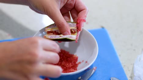 hands extracting finger lime pulp into a bowl on a kitchen counter with natural lighting
