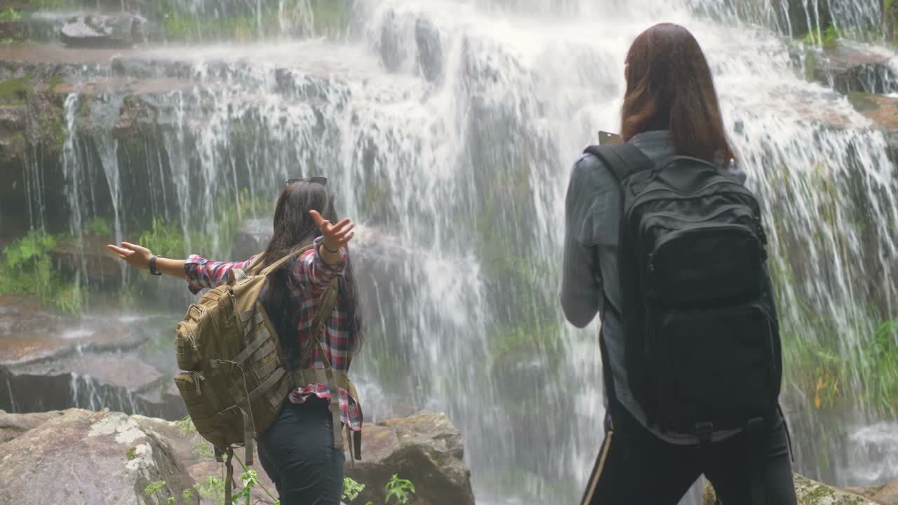 mujer extendiendo las manos disfrutando de la naturaleza bajo una cascada tropical dulce
