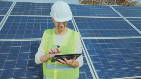 a worker in a helmet works with a tablet near a ground-based solar power station