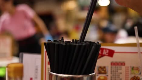 hand choosing chopsticks from a container