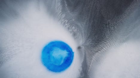 blue ink drop creating abstract patterns in white fluid under macro lens