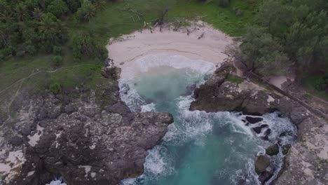 Arriba-Hacia-Abajo-De-La-Playa-De-Mandorak-En-La-Isla-De-Sumba-Con-Mar-Agitado-Durante-El-Amanecer,-Antena