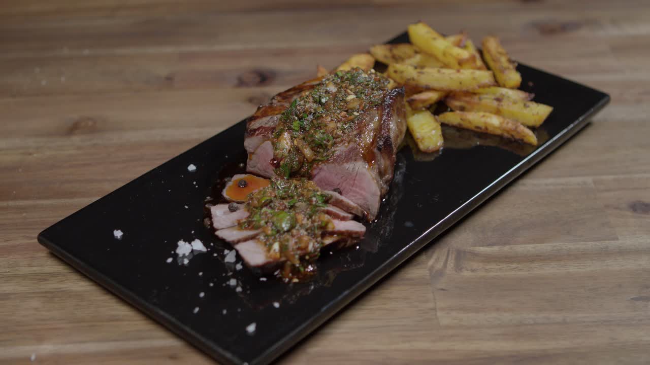 rebanadas de carne con chimichurri y mantequilla de café en parís en la tabla de cocina acompañadas de papas fritas, comida argentina