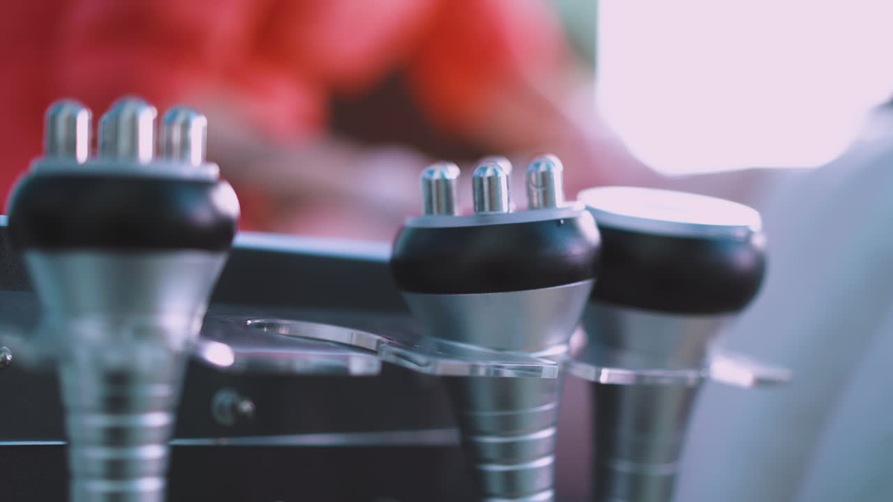 la esteticista toma el instrumento de vibromasaje para trabajar con el cliente