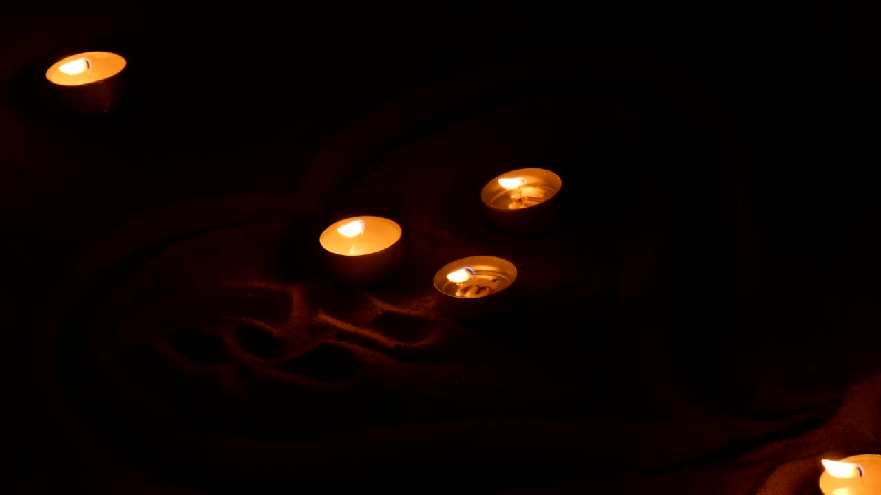 Candele bianche che bruciano nella sabbia