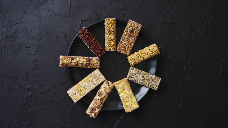 Different kind of granola fitness bars placed on black ceramic plate on a table