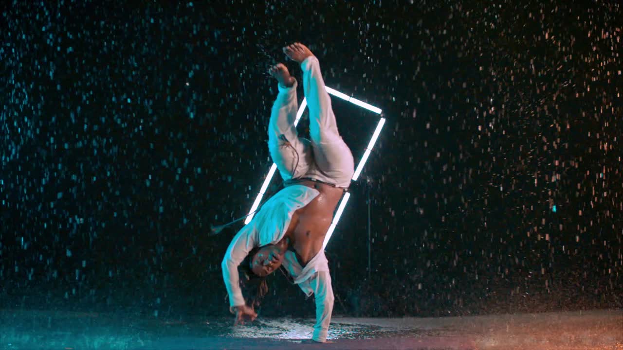 Capoeira dancer performing in the rain in super slow motion