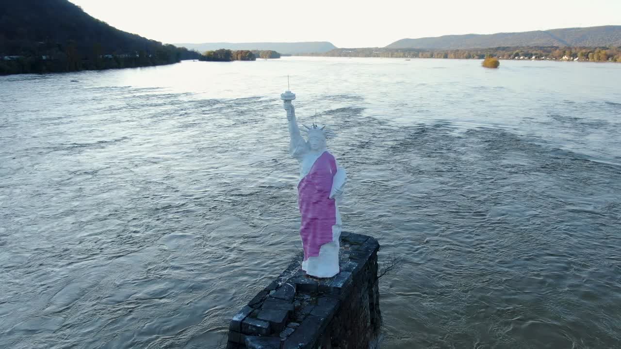 Close-up pan down of miniature Statue of Lady Liberty replica in Susquehanna River near Harrisburg PA, purple robe and torch