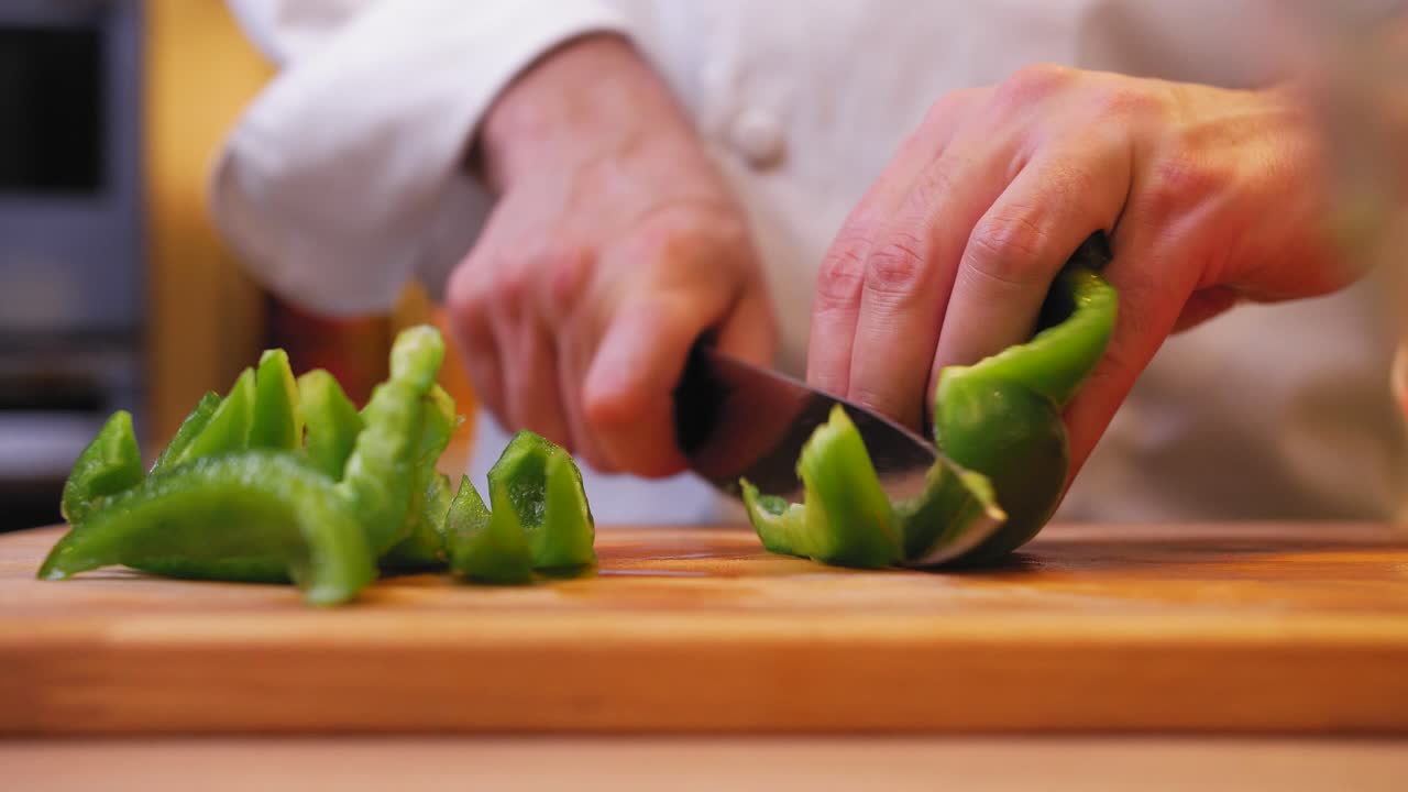 el cocinero está cortando pimientos verdes