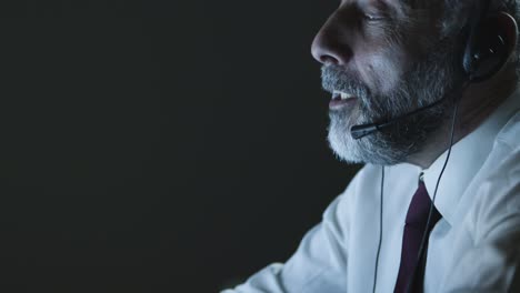 hombre de negocios maduro en auriculares usando computadora portátil