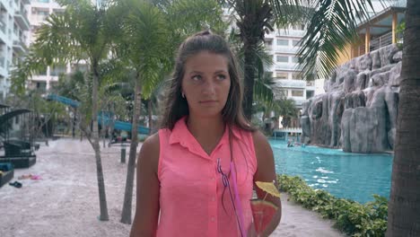 woman-walks-around-hotel-with-green-palms-and-grey-stones