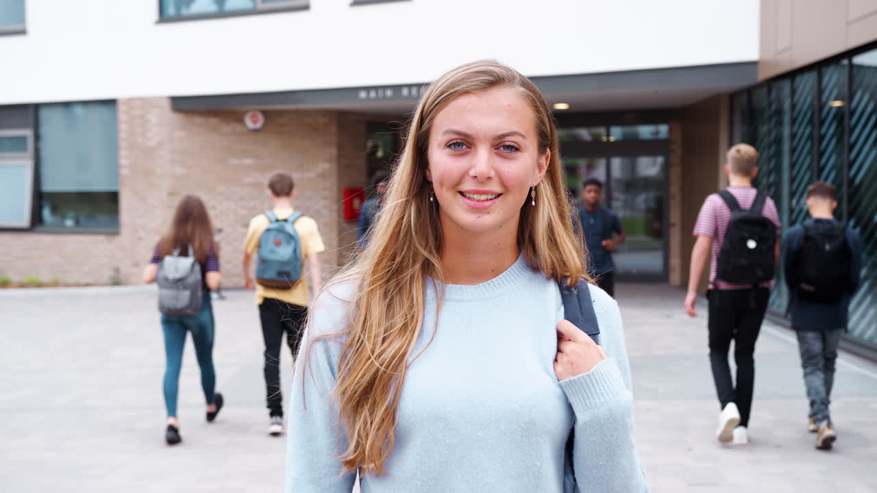 retrato de una estudiante de secundaria sonriente fuera del edificio de la universidad con otros estudiantes adolescentes en el fondo