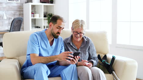 Médico-Varón-Enseñando-A-Una-Mujer-Mayor-A-Usar-Su-Teléfono